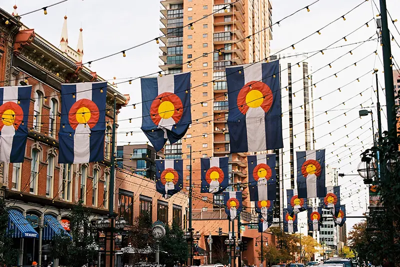 Let's Talk Gun Colorado - Picture of Colorado flags over street downtown denver